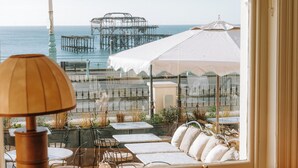 A seaside patio with tables and chairs, a lamp, and a view of the ocean and pier. - No. 124 Brighton (Brighton)