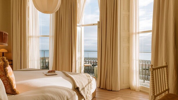 A bedroom with a large bed, a view of the sea, and a balcony with a railing. - No. 124 Brighton (Brighton)
