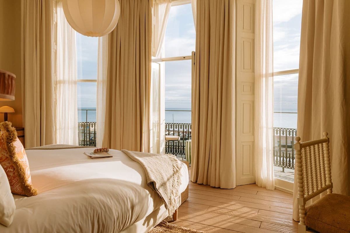 Un dormitorio con una cama grande, vista al mar y un balcón con barandilla.