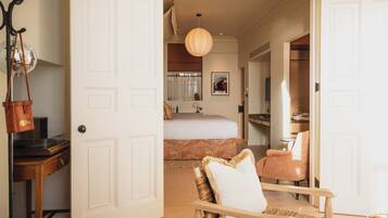 A hotel room with a bed, a chair, a desk, and a wardrobe.