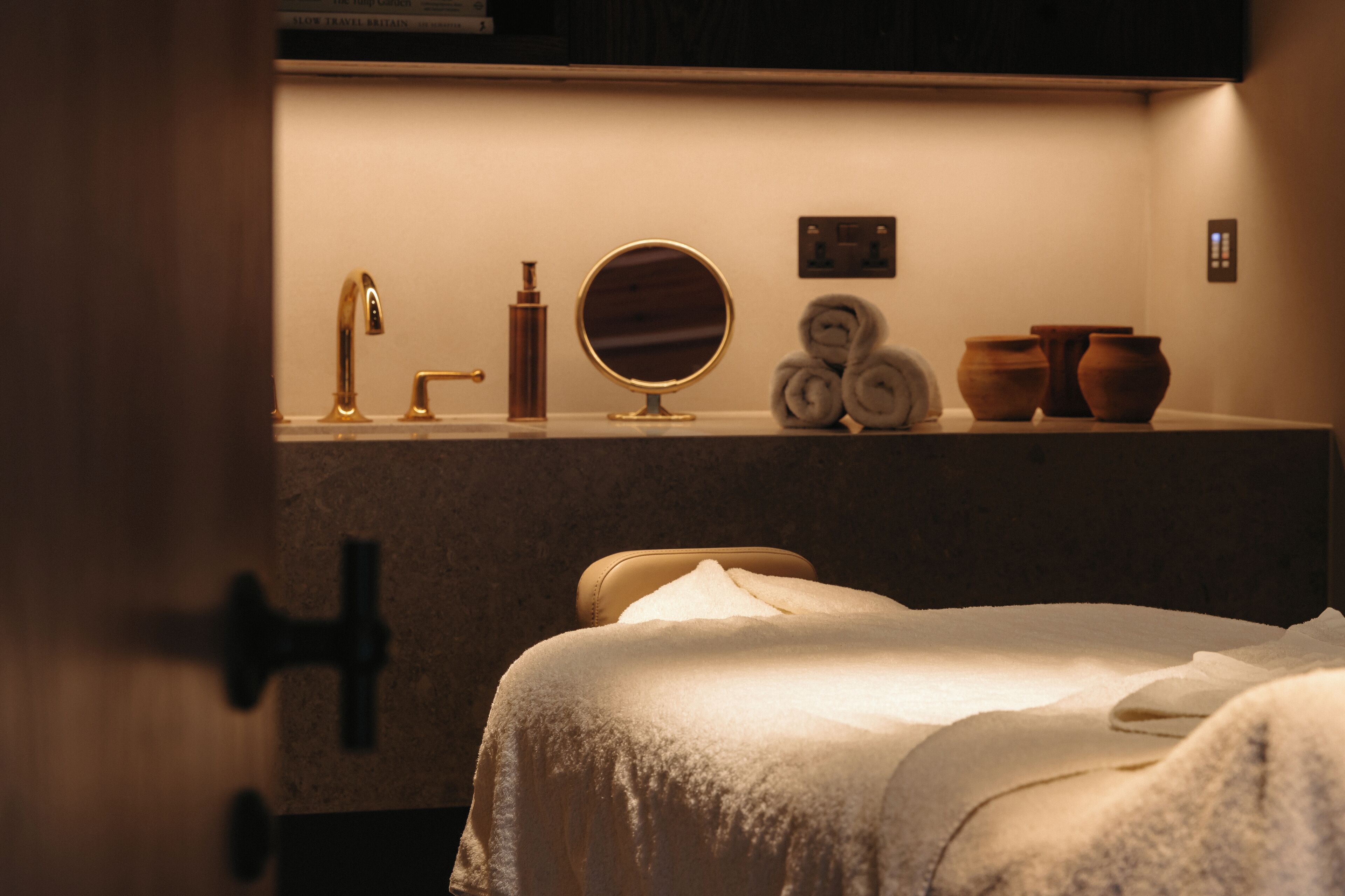 A hotel room with a bed, a sink with a mirror, and toiletries.
