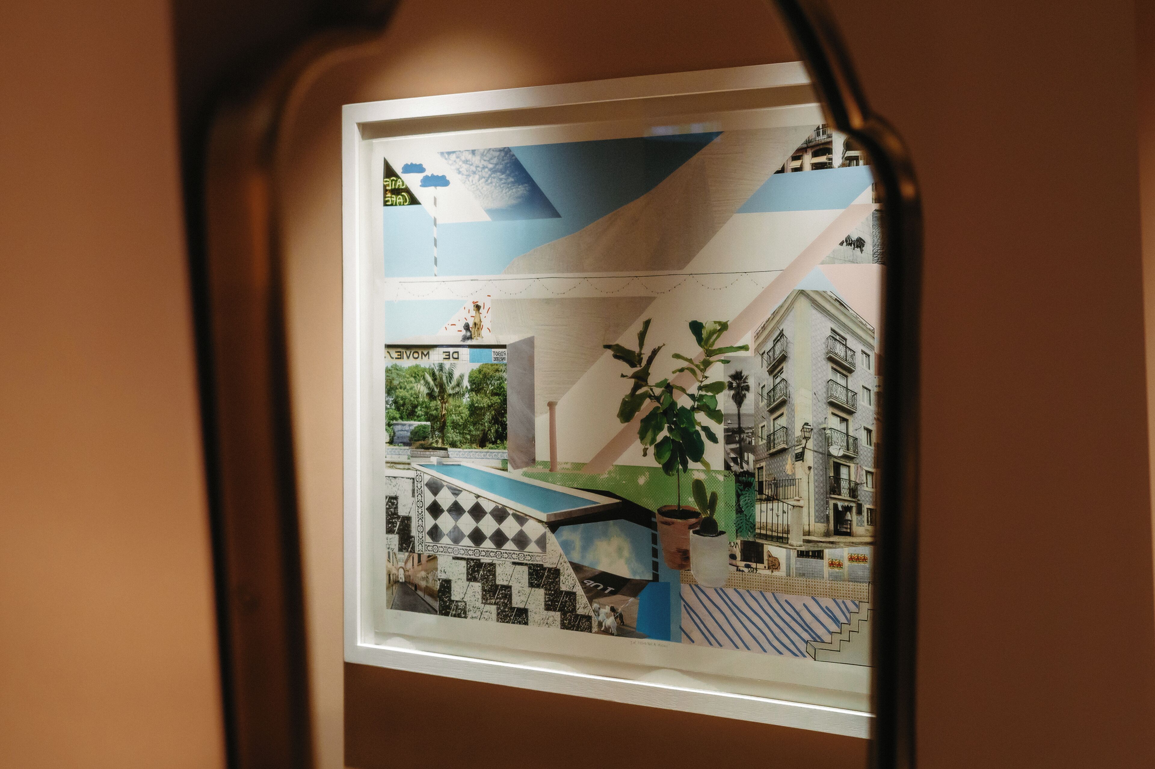 A view through a window with a geometric patterned design, a potted plant, and a building with balconies.