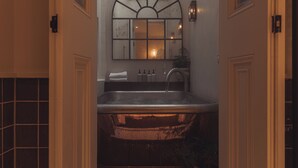 A bathroom with a freestanding bathtub, a mirror above the sink, and a towel rack. - No. 124 Brighton (Brighton)