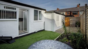 Ein weißes Haus mit kleinem Garten, Garage und Holzzaun.