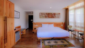 Hotellihuone, jossa on puinen sänky, työpöytä, tuoli ja pieni pöytä.