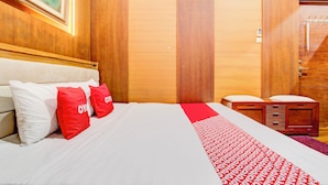 A hotel room with a bed, a wooden wardrobe, a clock, and a painting on the wall. - Hotel O Bestmela Homestay Syariah (Baturetno)