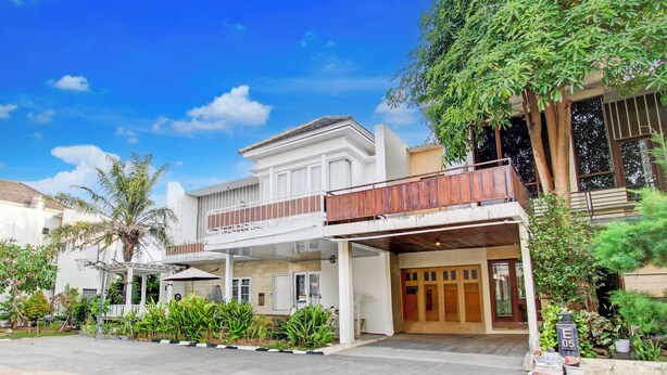 A two-story building with a balcony, a covered entrance, and a garden area with various plants. - Hotel O Bestmela Homestay Syariah (Baturetno)
