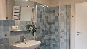A bathroom with a glass-enclosed shower, a sink, and a mirror. - Quiet 2 room apartment with WLAN on the first floor - MH5 (Markgrafenheide)