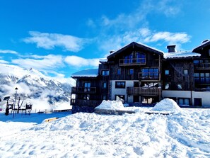 A multi-story wooden building with balconies, surrounded by snow and mountains. - Beautiful 3-Bed Apt in Plagne Montalbert with Fireplace, WIFI, Parking & Terrace (La Plagne Montalbert)
