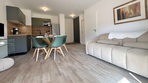 Un appartement moderne comprenant un coin repas, une kitchenette et un salon avec un canapé et un tableau.
