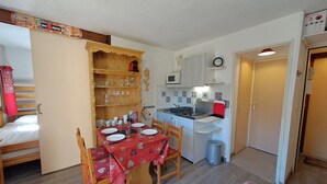 A compact kitchen with a dining table set for four, a microwave, and a small stove. - T2 Apartment with view, parking, 4 pers in Les Deux Alpes (Les Deux Alpes)