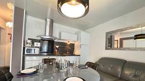 Un espace repas moderne avec une table ronde en verre, disposée pour quatre personnes, et entouré de canapés en cuir.