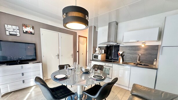 Une cuisine moderne avec un coin repas, comprenant une table ronde avec des chaises, un téléviseur et un canapé.