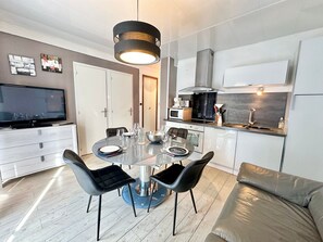 A modern kitchen with a dining area, including a round table with chairs, a television, and a sofa. - Apartment Vars, 2 bedrooms, 5 persons (Vars)