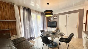 Un salon moderne avec un canapé en cuir, une table à manger avec des chaises, un téléviseur et un mur en bois.