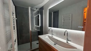 A modern bathroom with a glass-enclosed shower, a large mirror, and a wooden vanity with a sink. - Ski-in/Ski-out studio, 3 ppl, Méribel center, balcony, TV, fiber (Méribel)