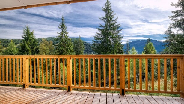 Eine Holzterrasse mit Geländer, mit Blick auf eine bewaldete Berglandschaft.