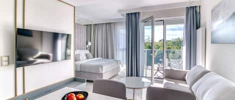 A modern hotel room with a bed, a dining area, and a balcony with a view.