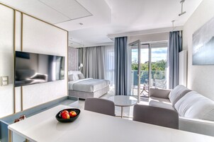 Una habitación de hotel moderna con cama, zona de comedor y balcón con vistas.