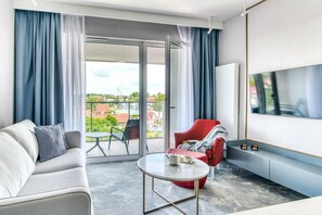 Suite – deluxe, balkong, bakgårdsutsikt | Oppholdsområde | En 50-tommers smart-TV med kabel-kanaler