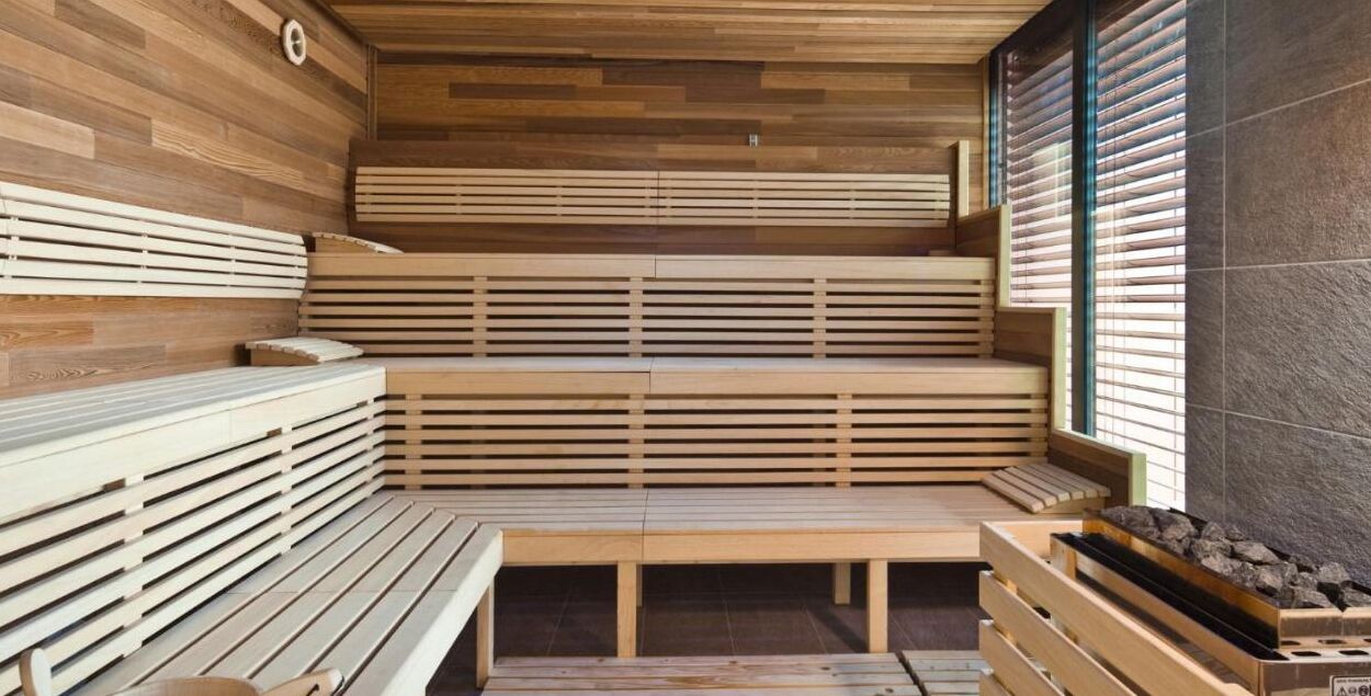 Eine Sauna mit Holzbänken und einer Steinwand.