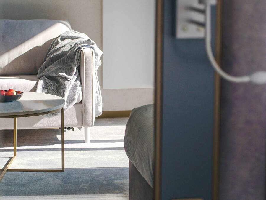 Una sala de estar moderna con un sofá, una mesa de centro con frutas, una lámpara y un cuadro en la pared.