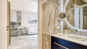 Une salle de bain moderne avec un grand lavabo en marbre, un miroir et un espace douche.