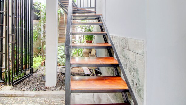 A staircase with wooden steps and metal railings, leading to an upper level. - Capital O 94314 Sunny Co Living (Banguntapan)