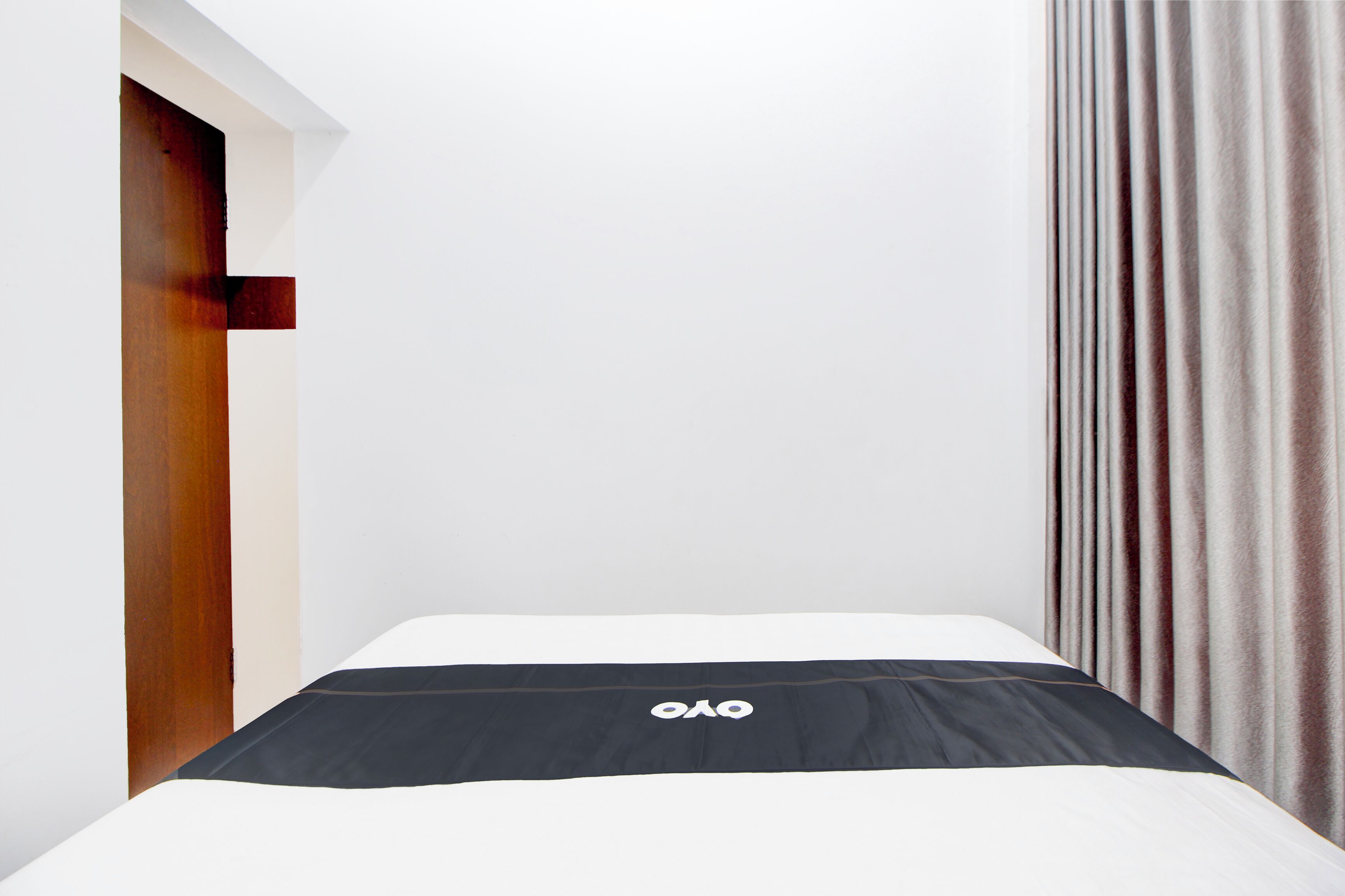 Ein Hotelzimmer mit einem Bett, einer Holztür und einem Vorhang.