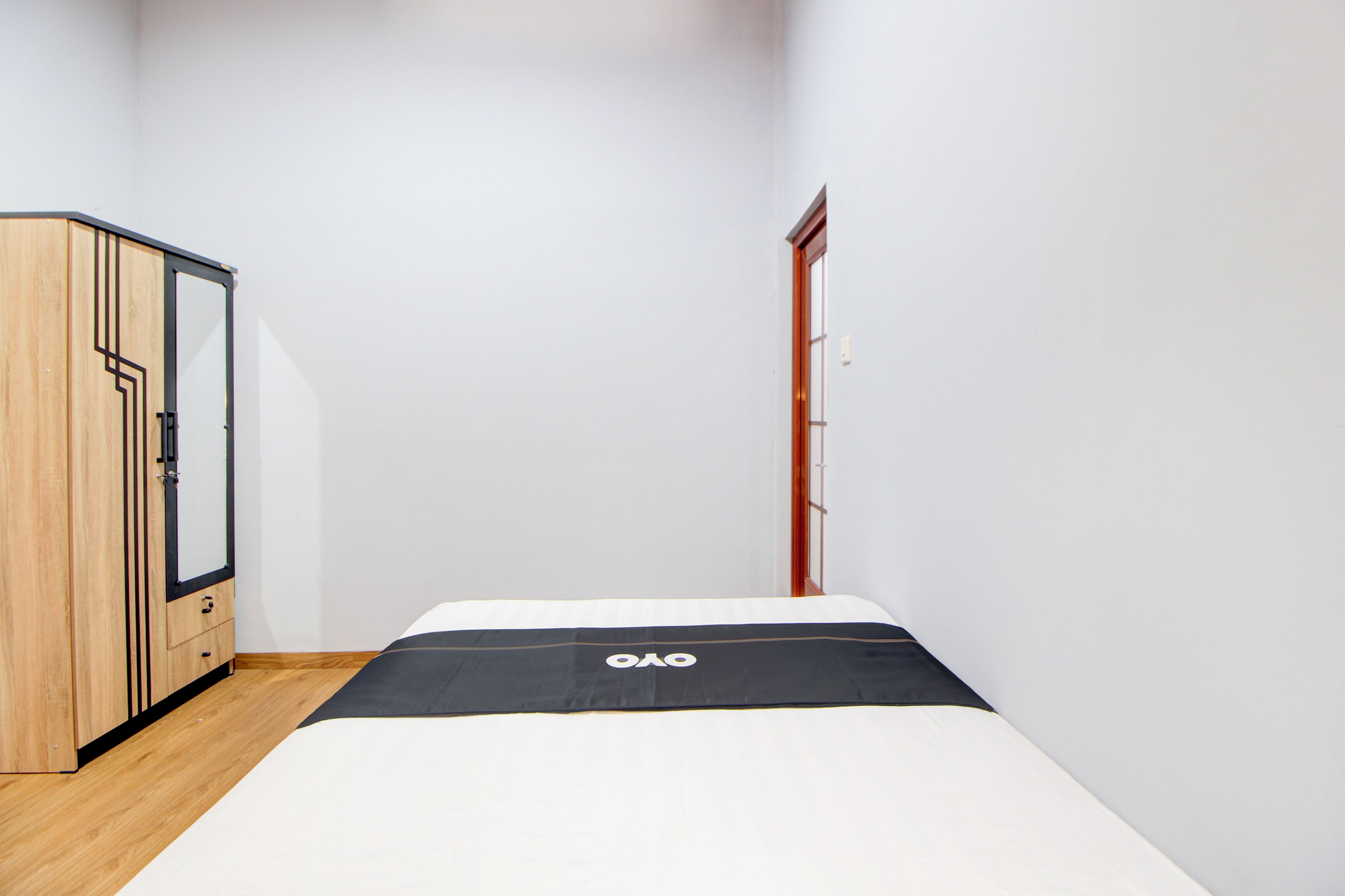 A bedroom with a bed, a wooden wardrobe, and a door.