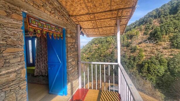 A stone building with a blue door and a thatched roof balcony. - Burans Kot Heritage Home - Ramgarh (Kosiyakutoli)