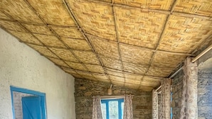 A room with a thatched roof, a bed, a desk, and a window with curtains. - Burans Kot Heritage Home - Ramgarh (Kosiyakutoli)