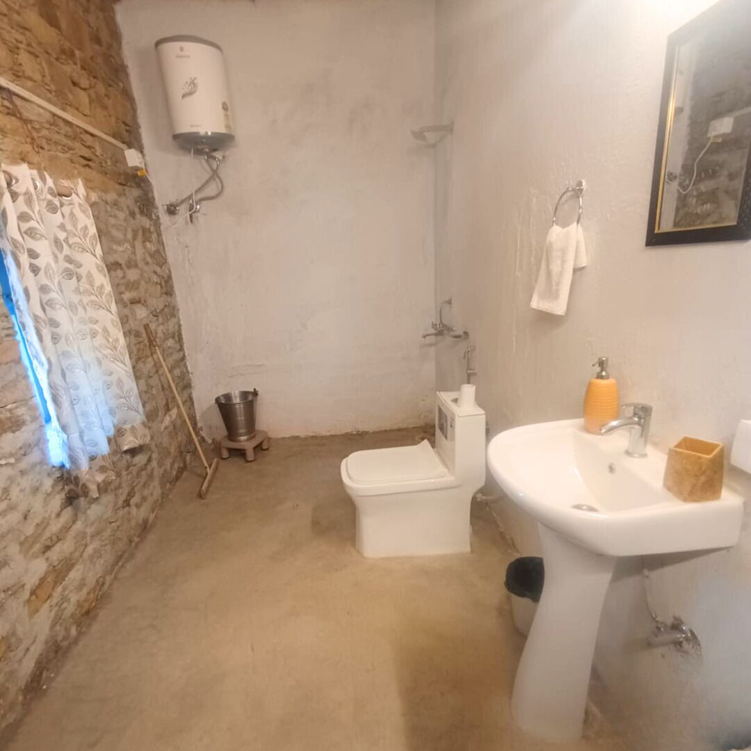 Een badkamer met een wit toilet, een wastafel, een douche en een aan de muur bevestigde boiler.
