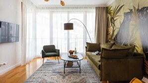 Ein Wohnzimmer mit einer Couch, einem Sessel, einem Couchtisch und einem Gemälde von Panthern.