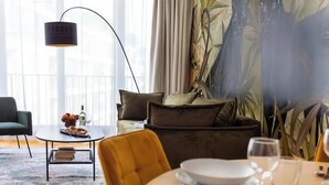 Ein modernes Wohnzimmer mit einer Couch, einem Couchtisch und einem Essbereich mit gedecktem Tisch für zwei Personen.