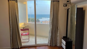 A room with a sliding glass door leading to a balcony with a view of the beach and ocean. - Ocean's Edge by Natti's group (Visakhapatnam)