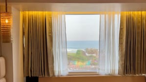 A room with a large window, a sofa, and a hanging light fixture. - Ocean's Edge by Natti's group (Visakhapatnam)