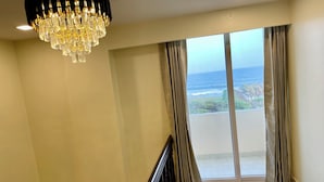 A spacious balcony with a view of the ocean, a modern chandelier, and a clean, minimalist interior. - Ocean's Edge by Natti's group (Visakhapatnam)