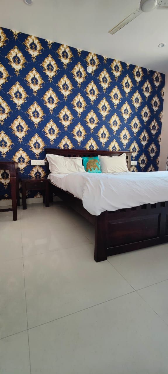 A bedroom with a bed, a nightstand, and a patterned wallpaper.