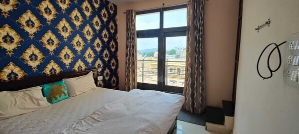 Une chambre d’hôtel avec un grand lit, un mur décoré d’un motif, une fenêtre avec des rideaux et une prise électrique fixée au mur.