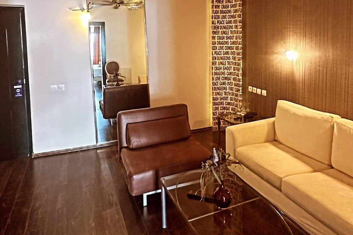 A modern living room with a ceiling fan, a brown leather sofa, a white sofa, and a glass coffee table.
