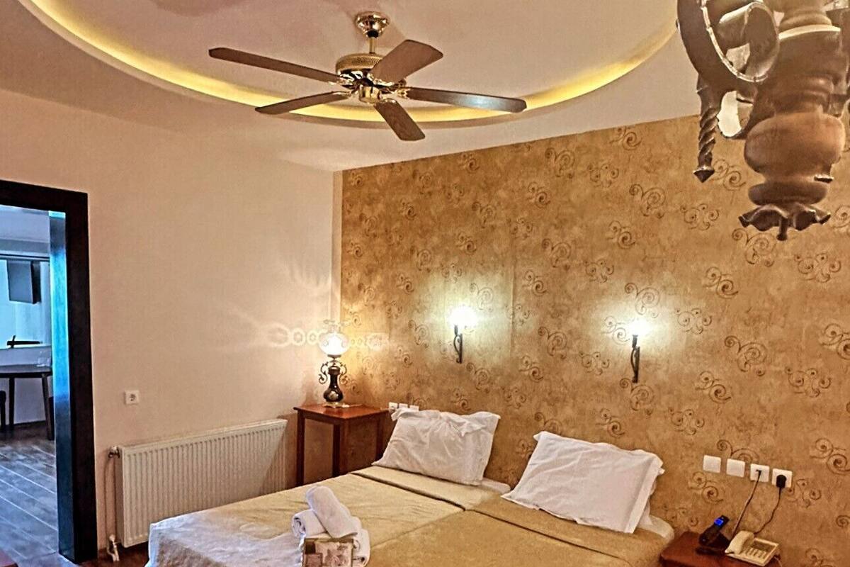 A bedroom with a double bed, a ceiling fan, a chandelier, and a radiator.