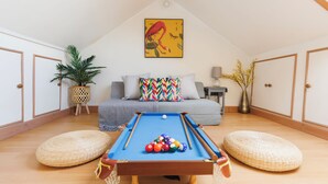 A cozy room with a pool table, a sofa, and a painting on the wall.