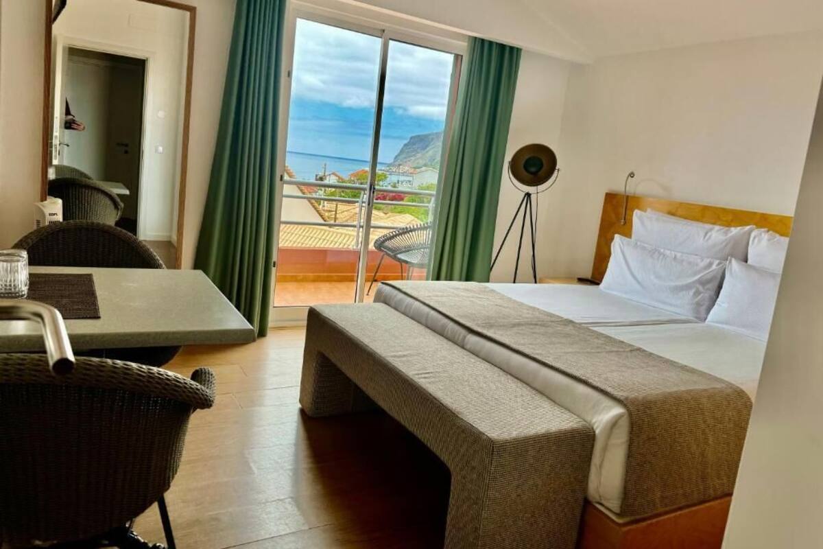 A hotel room with a bed, a bench, a table, and a chair.
