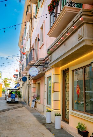 A street view of a hotel with balconies, string lights, and potted plants. - Bella hotel Phu Quoc (Phu Quoc)