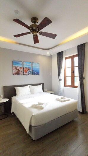 A hotel room with a bed, a ceiling fan, a window with curtains, and two paintings on the wall. - Bella hotel Phu Quoc (Phu Quoc)