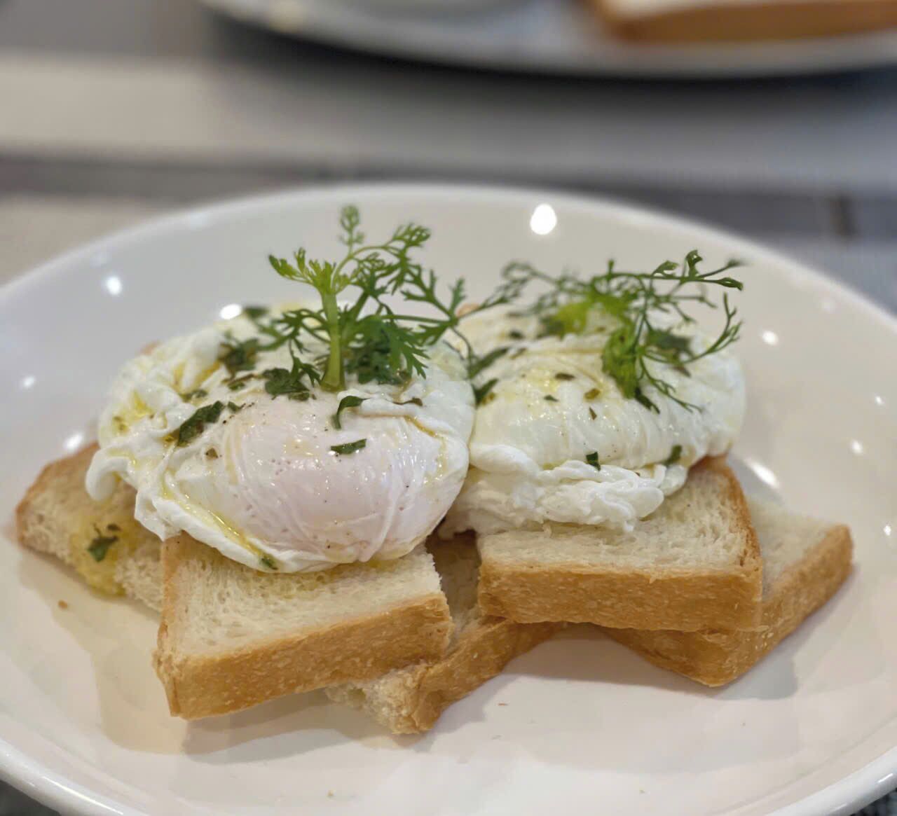 Un plato con dos huevos pochados sobre tostada, adornado con hierbas.