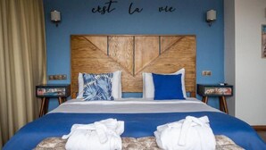 Ein Hotelzimmer mit einem Bett, zwei Nachttischen, einer Wand mit einem französischen Spruch und Handtüchern auf dem Bett.