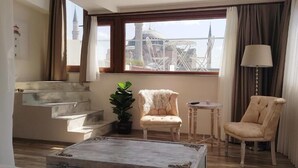 Ein modernes Wohnzimmer mit Treppe, einer Zimmerpflanze, zwei Sesseln, einem kleinen Tisch und einer Lampe.
