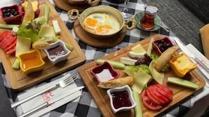 Ein Tisch mit karierter Oberfläche, reichlich mit Speisen wie Eiern, Brot und Gemüse belegt, steht im Freien.